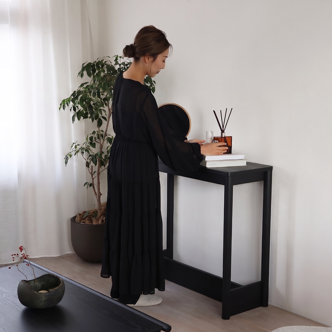 コヤバリコンソールテーブルにインテリア雑貨を飾る女性