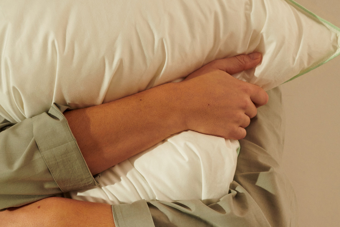 枕を手で抱きしめた様子