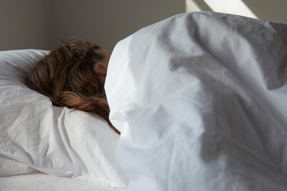 枕と掛け布団を使用する女性
