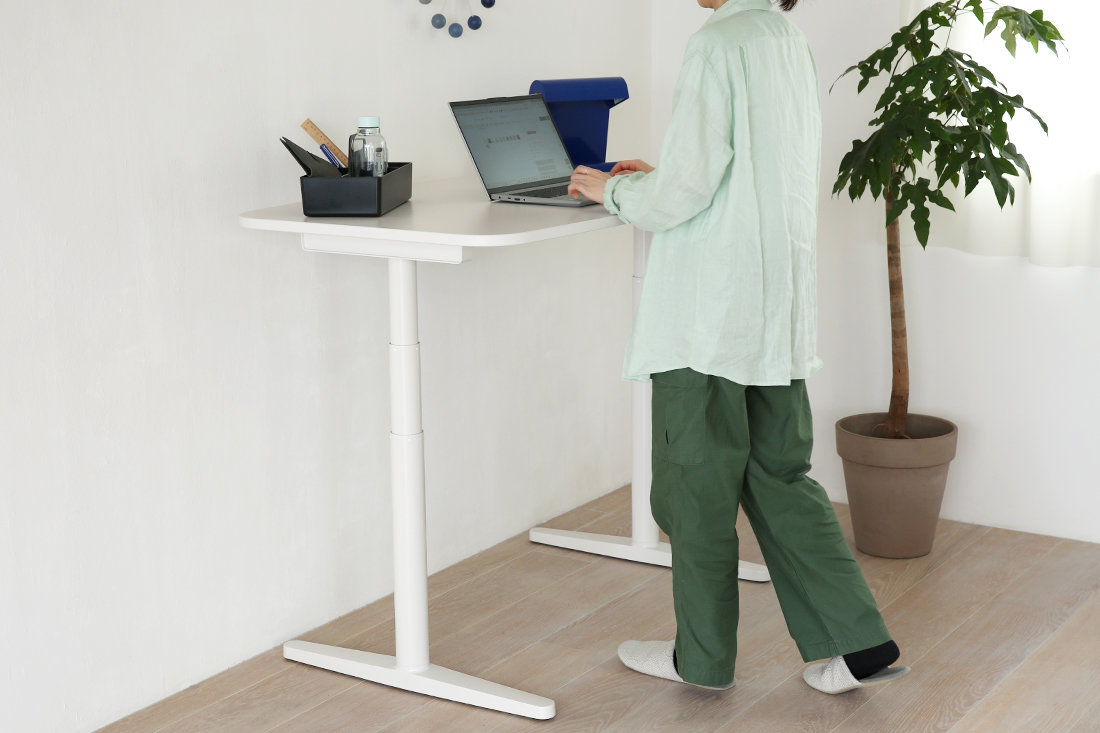 昇降デスクでPC作業をしている女性